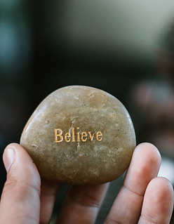 believe in yourself person holding stone that says believe