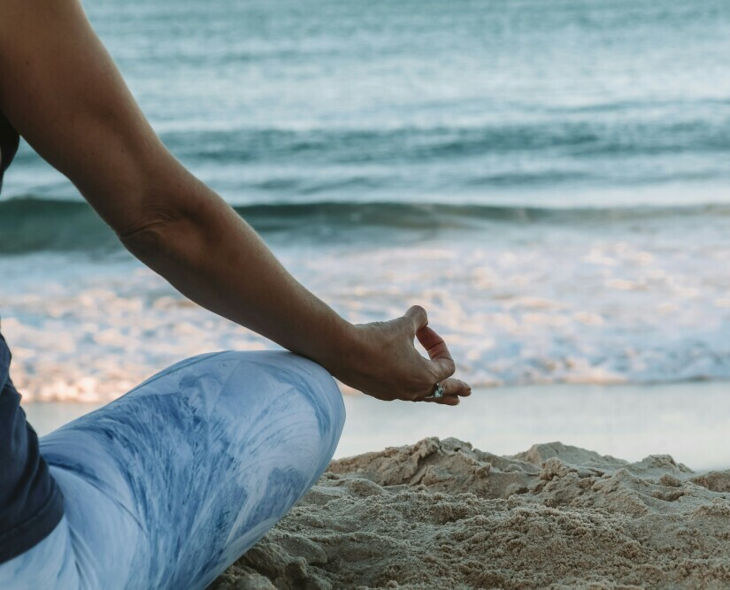 someone meditating on beach.  